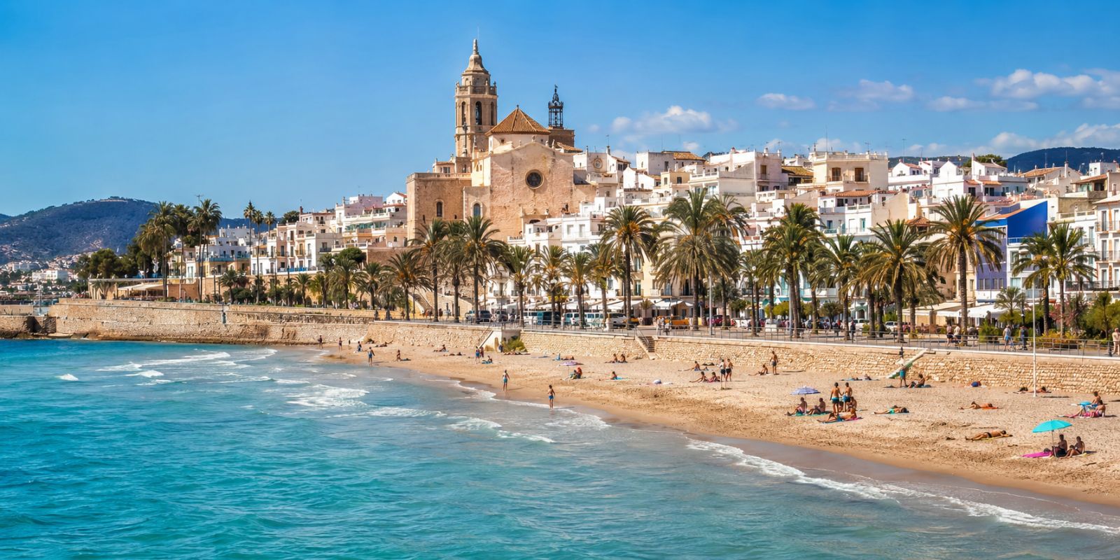 Plage de Sitges avec l’église Sant Bartomeu i Santa Tecla, maisons blanches et mer Méditerranée sur la Costa Barcelona